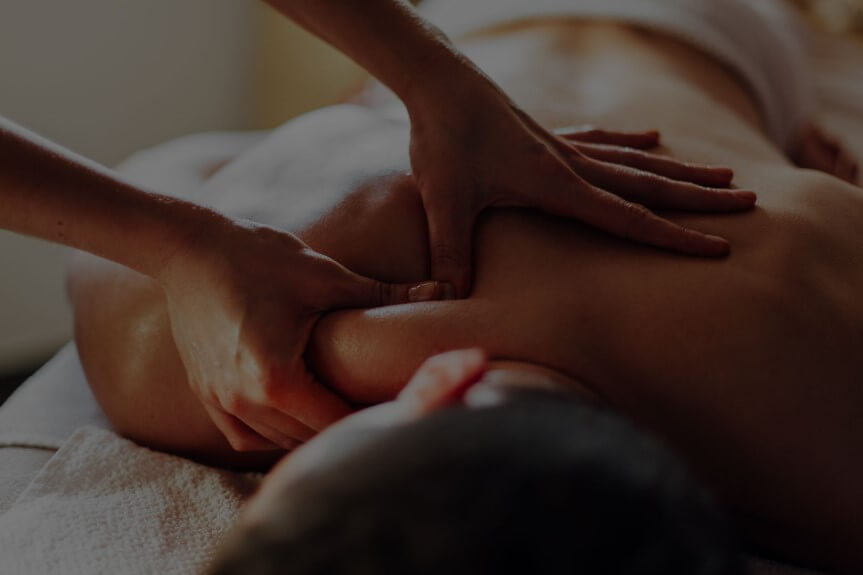 Person receiving a back massage from a therapist with focus on the hands applying pressure.